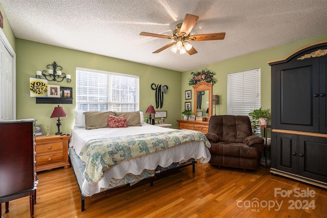 bedroom with ceiling fan, wood-type flooring, and a textured ceiling