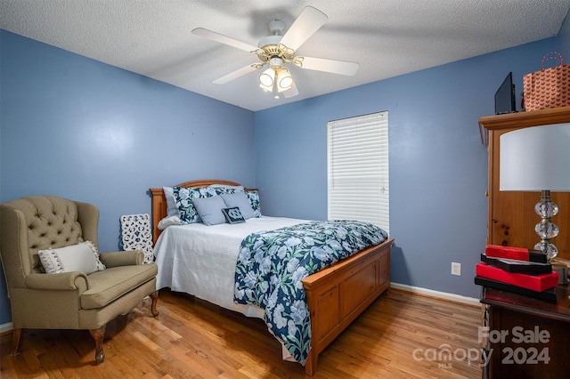 bedroom with ceiling fan, light wood-type flooring, and a textured ceiling