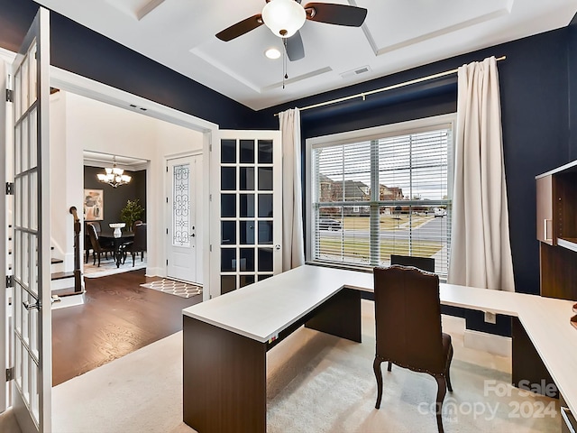 office area with hardwood / wood-style flooring, ceiling fan with notable chandelier, french doors, and a tray ceiling