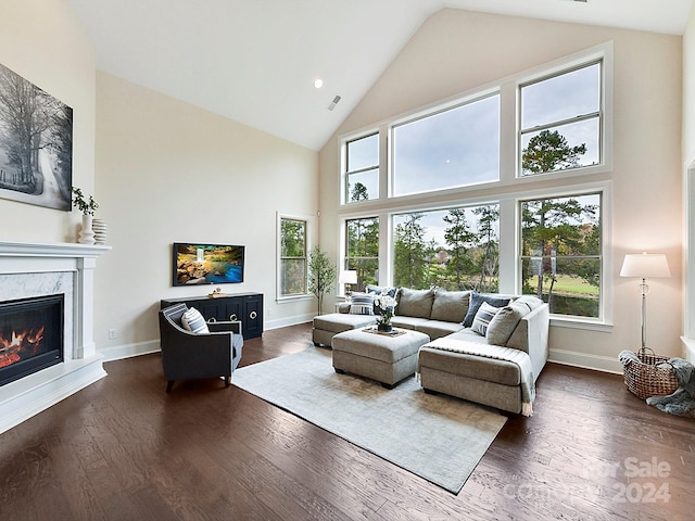 living room featuring plenty of natural light, dark wood-type flooring, and high vaulted ceiling