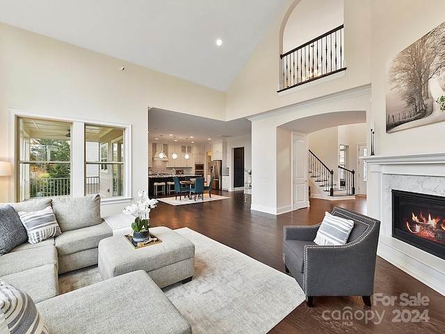 living room featuring high vaulted ceiling, dark wood-type flooring, and a premium fireplace