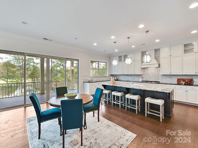 dining space with dark hardwood / wood-style floors, crown molding, and sink