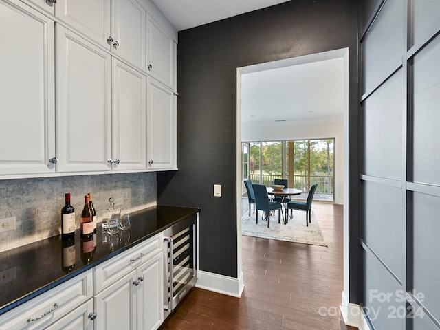 bar featuring decorative backsplash, dark hardwood / wood-style flooring, ornamental molding, beverage cooler, and white cabinets