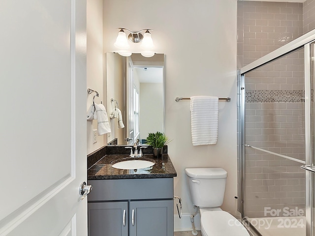 bathroom with walk in shower, vanity, and toilet