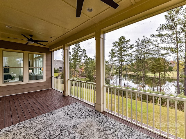 unfurnished sunroom featuring ceiling fan and a water view