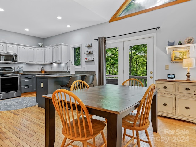 dining room with a healthy amount of sunlight, vaulted ceiling, and light hardwood / wood-style flooring