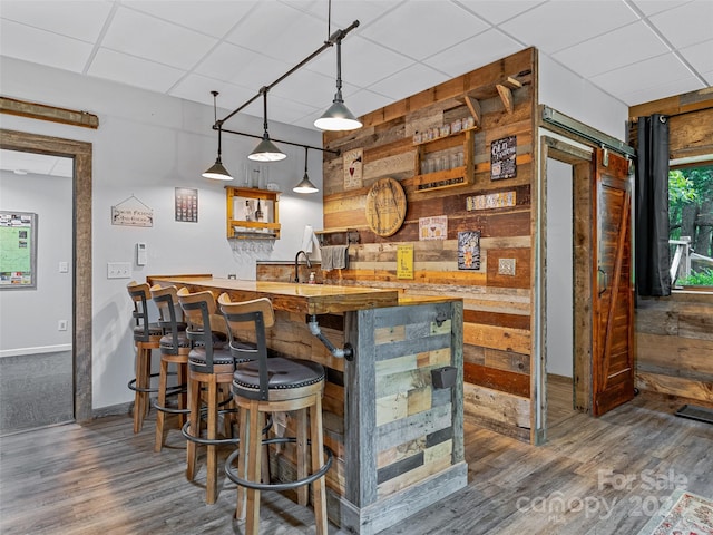 bar with a paneled ceiling, pendant lighting, and dark hardwood / wood-style floors