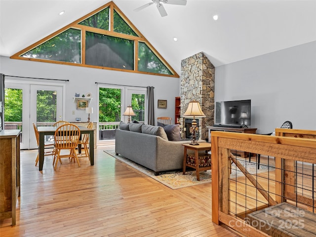 living area featuring high vaulted ceiling, ceiling fan, and light wood-style flooring