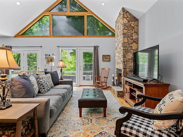 living area featuring french doors, high vaulted ceiling, a stone fireplace, and wood finished floors