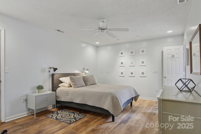 bedroom with hardwood / wood-style flooring, a textured ceiling, and ceiling fan