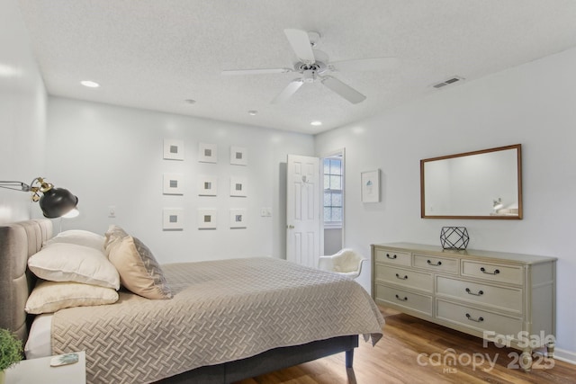 bedroom featuring ceiling fan, a textured ceiling, and light hardwood / wood-style floors