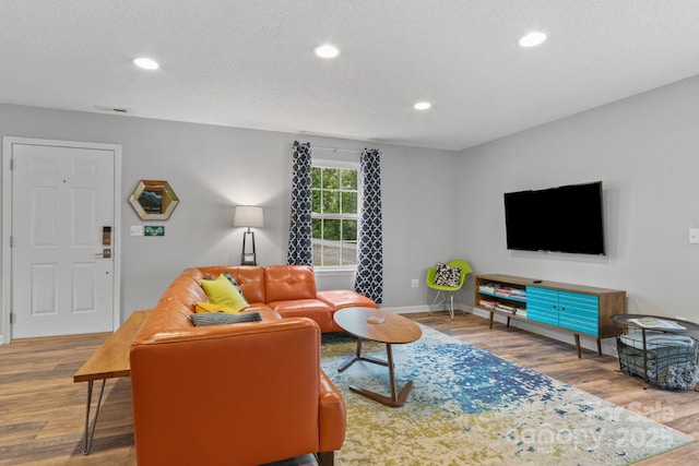 living area with a textured ceiling, wood finished floors, recessed lighting, and baseboards