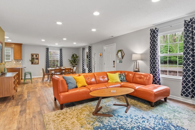living room with plenty of natural light, recessed lighting, light wood-style flooring, and baseboards