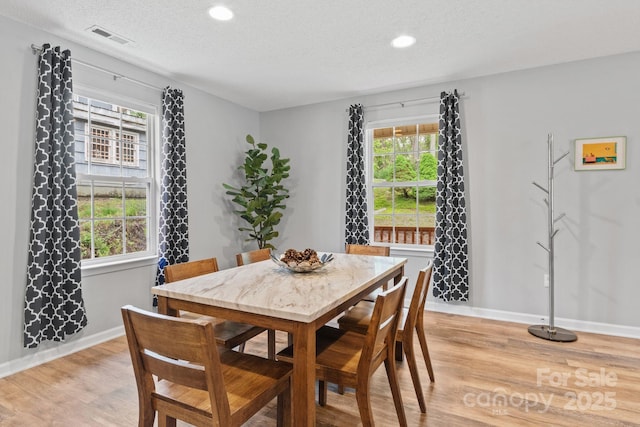 dining space with visible vents, a wealth of natural light, and light wood-style floors