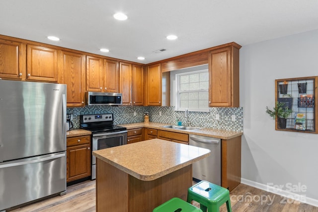 kitchen with appliances with stainless steel finishes, brown cabinets, and a sink