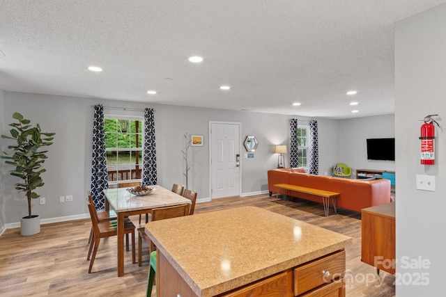 kitchen with a textured ceiling, light countertops, baseboards, recessed lighting, and light wood finished floors