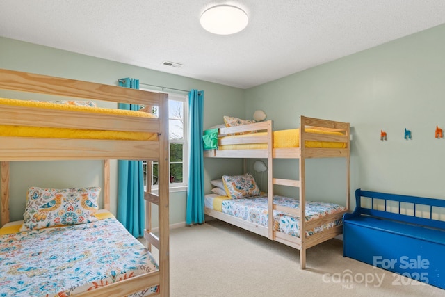 bedroom featuring a textured ceiling, visible vents, carpet, and baseboards
