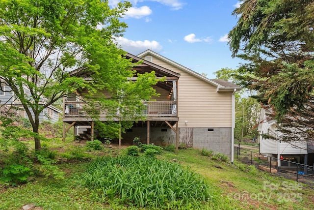 back of property featuring fence, a wooden deck, and crawl space