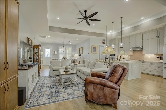 living room featuring ceiling fan with notable chandelier and light hardwood / wood-style floors