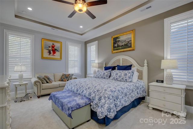 carpeted bedroom with ceiling fan, crown molding, and a raised ceiling