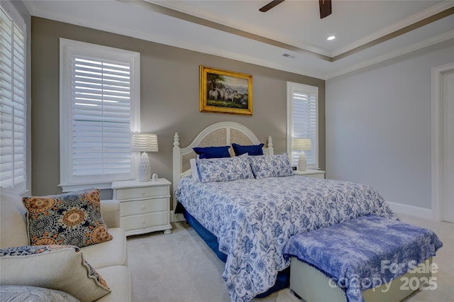 bedroom with ceiling fan, light carpet, a tray ceiling, and ornamental molding