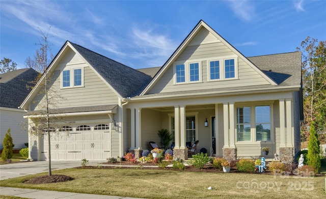 view of front of house featuring covered porch, a garage, and a front lawn