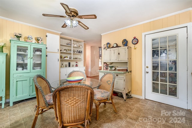 dining room featuring ceiling fan, wood walls, and crown molding