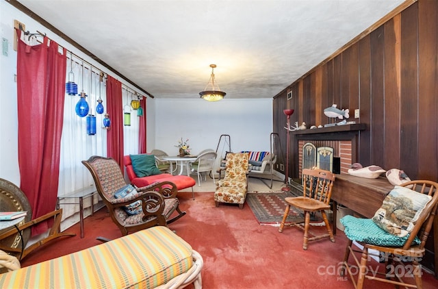 sitting room with a fireplace, carpet floors, ornamental molding, and wood walls