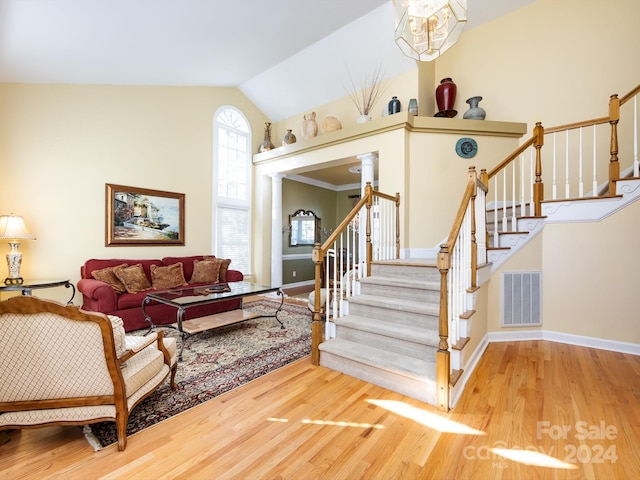 living room with decorative columns, vaulted ceiling, hardwood / wood-style flooring, and crown molding