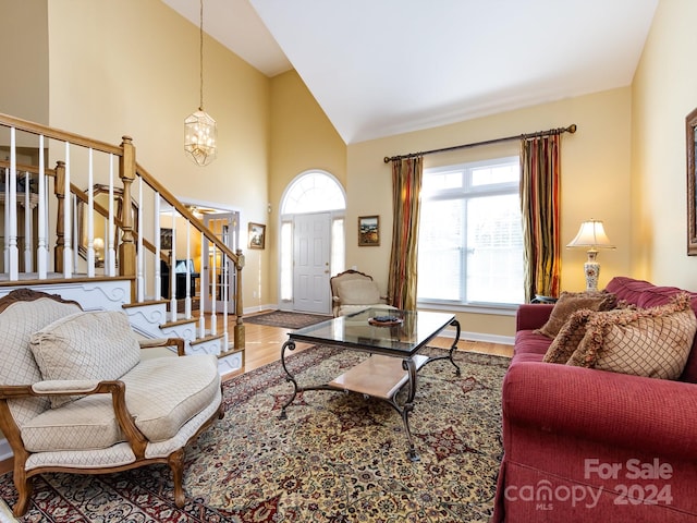 living room with hardwood / wood-style floors, high vaulted ceiling, and a notable chandelier