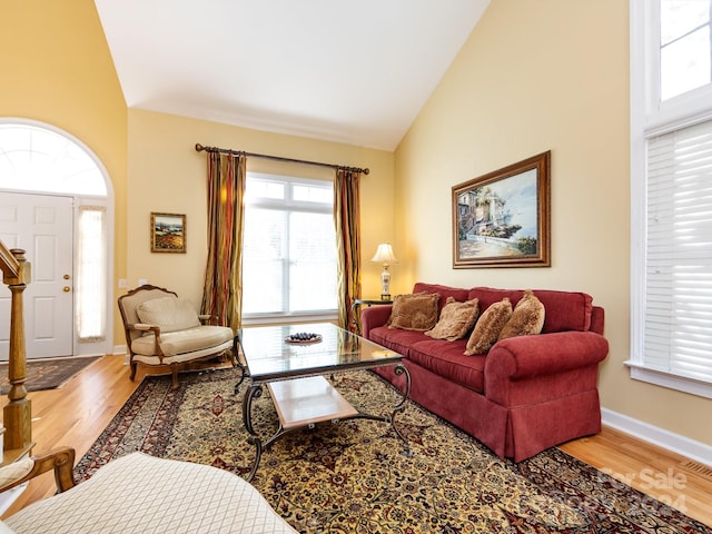 living room with high vaulted ceiling, a healthy amount of sunlight, and hardwood / wood-style flooring