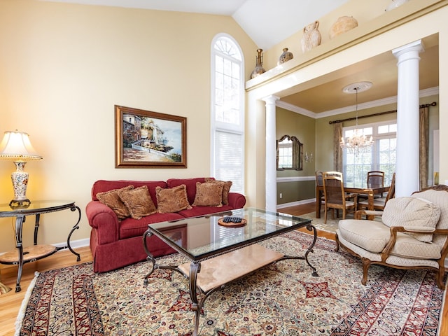 living room with hardwood / wood-style floors, crown molding, vaulted ceiling, ornate columns, and a chandelier