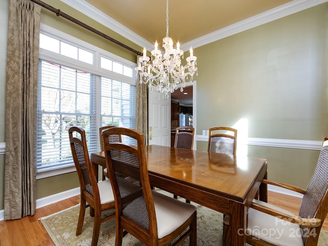 dining room with a notable chandelier, light wood-type flooring, and ornamental molding