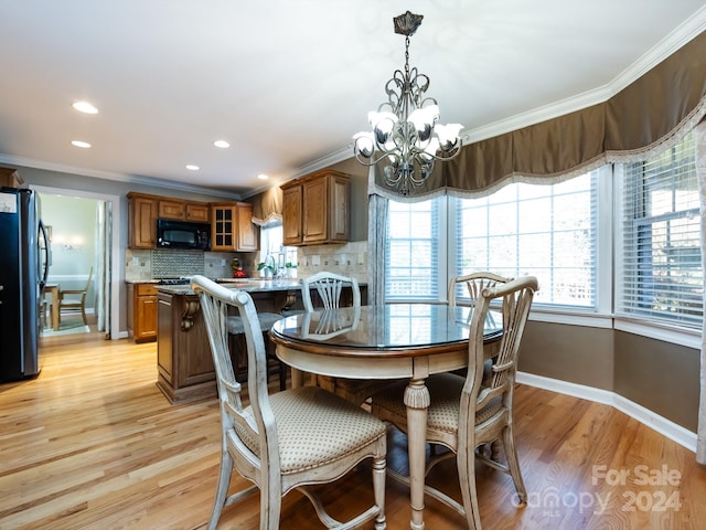 dining area with light hardwood / wood-style floors, an inviting chandelier, ornamental molding, and sink