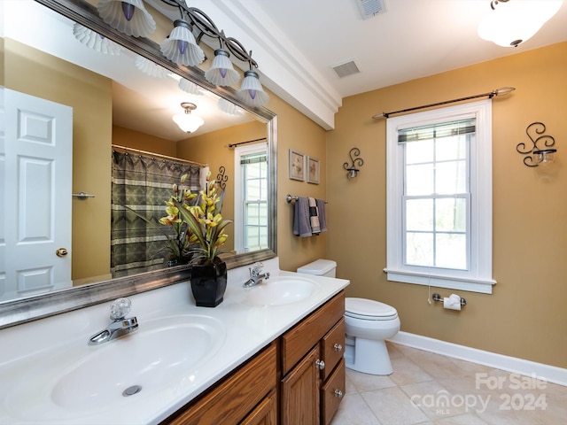 bathroom featuring tile patterned flooring, vanity, toilet, and a healthy amount of sunlight