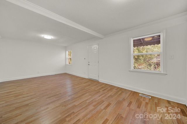 empty room with crown molding and light hardwood / wood-style floors