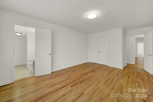 unfurnished bedroom featuring connected bathroom, light hardwood / wood-style floors, and a closet