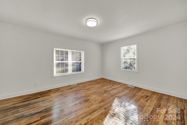 empty room with hardwood / wood-style floors and ornamental molding