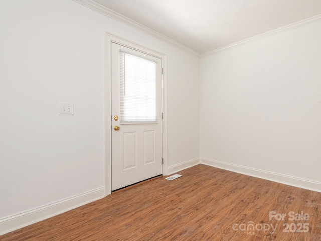 spare room with light wood finished floors, ornamental molding, visible vents, and baseboards