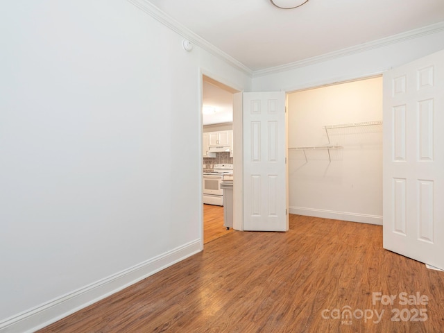 unfurnished bedroom featuring light wood-style floors, baseboards, ornamental molding, and a closet