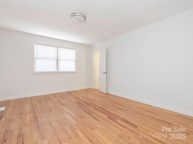 spare room featuring light wood-style flooring and baseboards