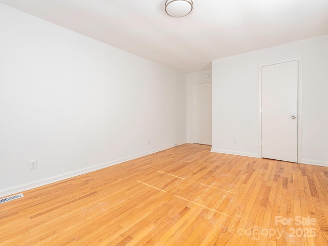 unfurnished bedroom with light wood finished floors, visible vents, and baseboards