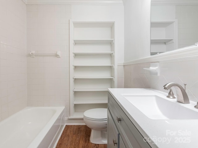 bathroom featuring toilet, wood finished floors, vanity, tile walls, and backsplash