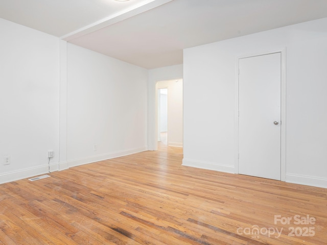 unfurnished room featuring light wood-type flooring, visible vents, and baseboards