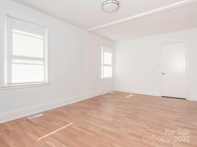 empty room featuring light wood-style floors, visible vents, and baseboards