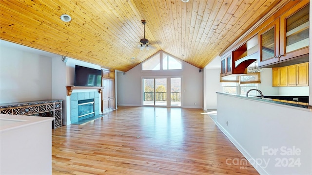 unfurnished living room with a tile fireplace, light wood-type flooring, ceiling fan, and wooden ceiling