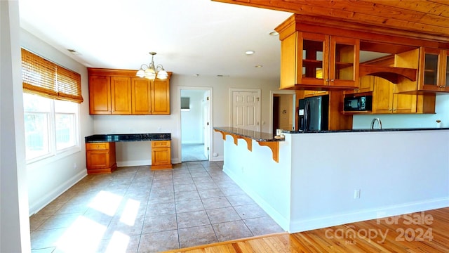 kitchen featuring hanging light fixtures, an inviting chandelier, light hardwood / wood-style flooring, a breakfast bar area, and black appliances