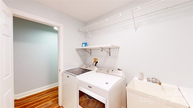 laundry room featuring washing machine and dryer, hardwood / wood-style flooring, and sink