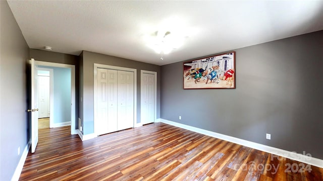 unfurnished bedroom with hardwood / wood-style floors and two closets