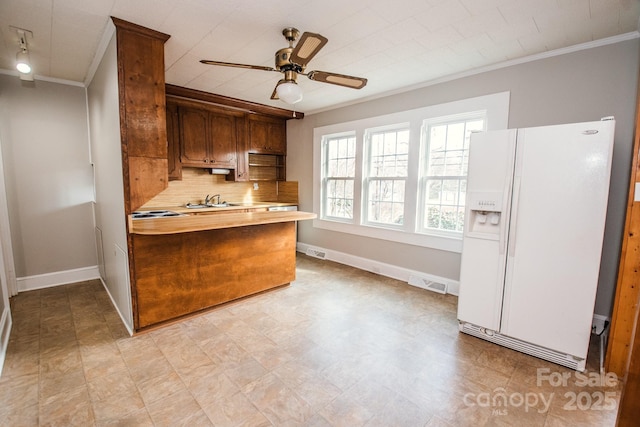 kitchen with kitchen peninsula, backsplash, white fridge with ice dispenser, and ornamental molding